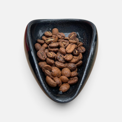 Nærbilde av kaffebønner i porselenskål rett etter bruk av ross droplet technique med doseringssett for kaffebønner.