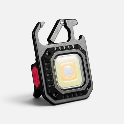 Mini LED-lommelykt sett fra siden med karabinkrok og et rødt ladedeksel synlig.